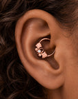 Rose gold leaf conch piercing ring with a small pearl on a person's ear
