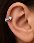 Silver leaf helix piercing with a small pearl on a person's ear
