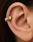 18k gold leaf helix earring with a small pearl on a person's ear