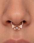 Close-up of a rose gold septum piercing ring featuring a bow design with a central pearl