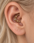 18k gold conch piercing ring with a pearl and diamond leaf design in a woman's ear