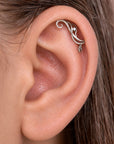 Close-up of a silver filigree helix piercing with a small diamond in a human ear.