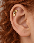 Close-up of a gold leaf cartilage piercing with a small pearl in a human ear