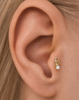 18k gold leaf-shaped tragus piercing with a pearl and small diamond on a human ear