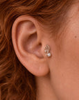 Close-up of a gold leaf and pearl stud earring in a woman's ear lobe
