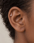 Close-up of a rose gold helix piercing with a small pearl on a person's ear