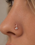 Rose gold nose stud piercing with a pearl and diamond accent on a woman's nose