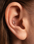 Rose gold flower-shaped stud earring with a pearl center in a tragus piercing