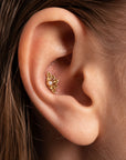18k gold flower tragus piercing with a pearl center on a person's ear