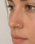 Close-up of a woman wearing an 18k gold nose ring with a marquise diamond