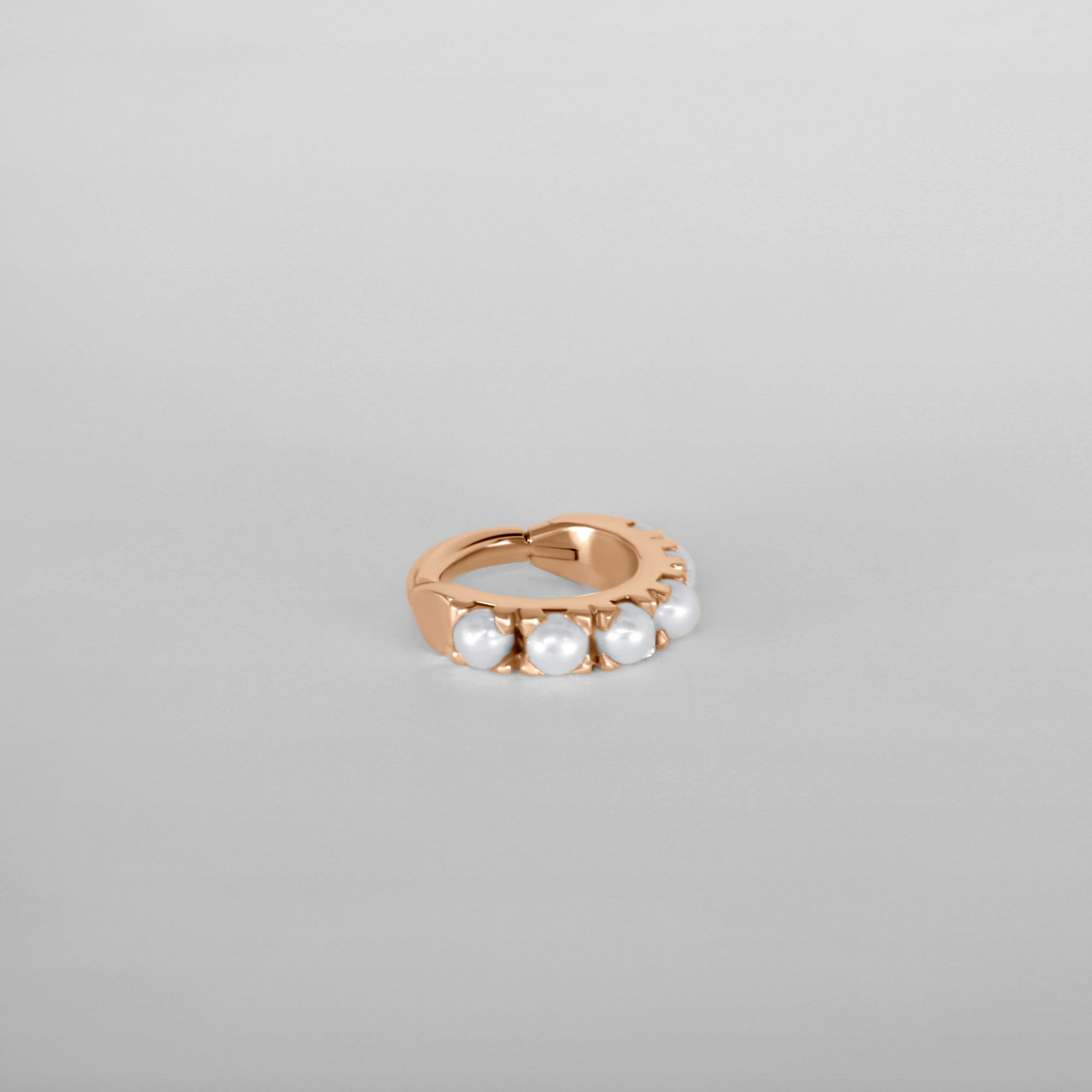 Close up of the Luméa hoop piercing in 18k rose gold adorned with freshwater pearls