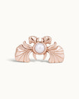 Rose gold piercing jewelry featuring a central white pearl and fan-like wing details.
