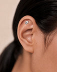 Delicate 18k gold ear piercing with textured disc design, handmade luxury body jewelry for elegant style.