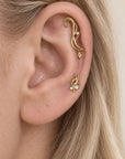 Woman's ear with luxury 18k gold helix and lobe piercings featuring precious stones