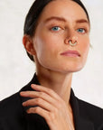 Woman wearing an 18k gold diamond septum piercing, luxury handmade nose jewelry