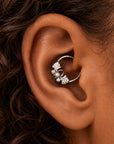 Silver leaf-shaped cartilage piercing hoop with a small pearl detail on a person's ear