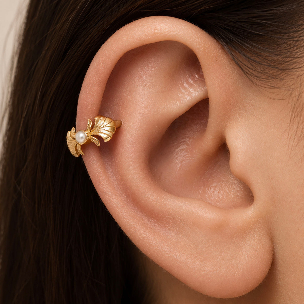 18k gold leaf helix earring with a small pearl on a person's ear