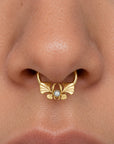 Close-up of a luxury 18k gold septum ring with a pearl and ornate floral design.