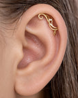 18k gold ornate helix piercing jewelry with a small diamond in a woman's ear