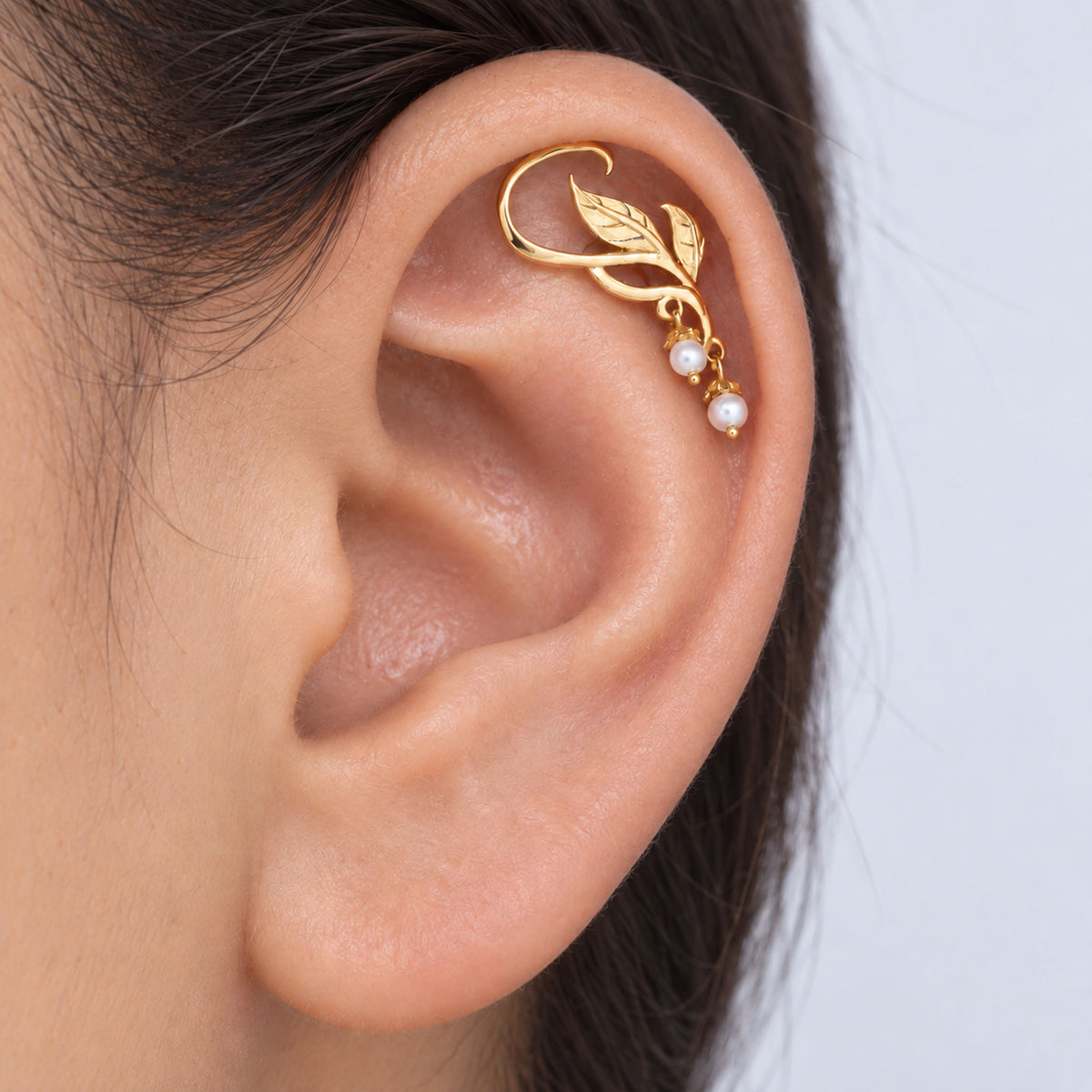 18k gold leaf ear cuff with small pearls on a woman's ear