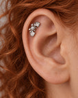 Close-up of a silver leaf and pearl helix piercing in a person's ear.