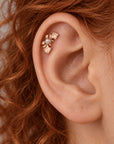 18k gold leaf helix piercing with a small pearl on a person's ear