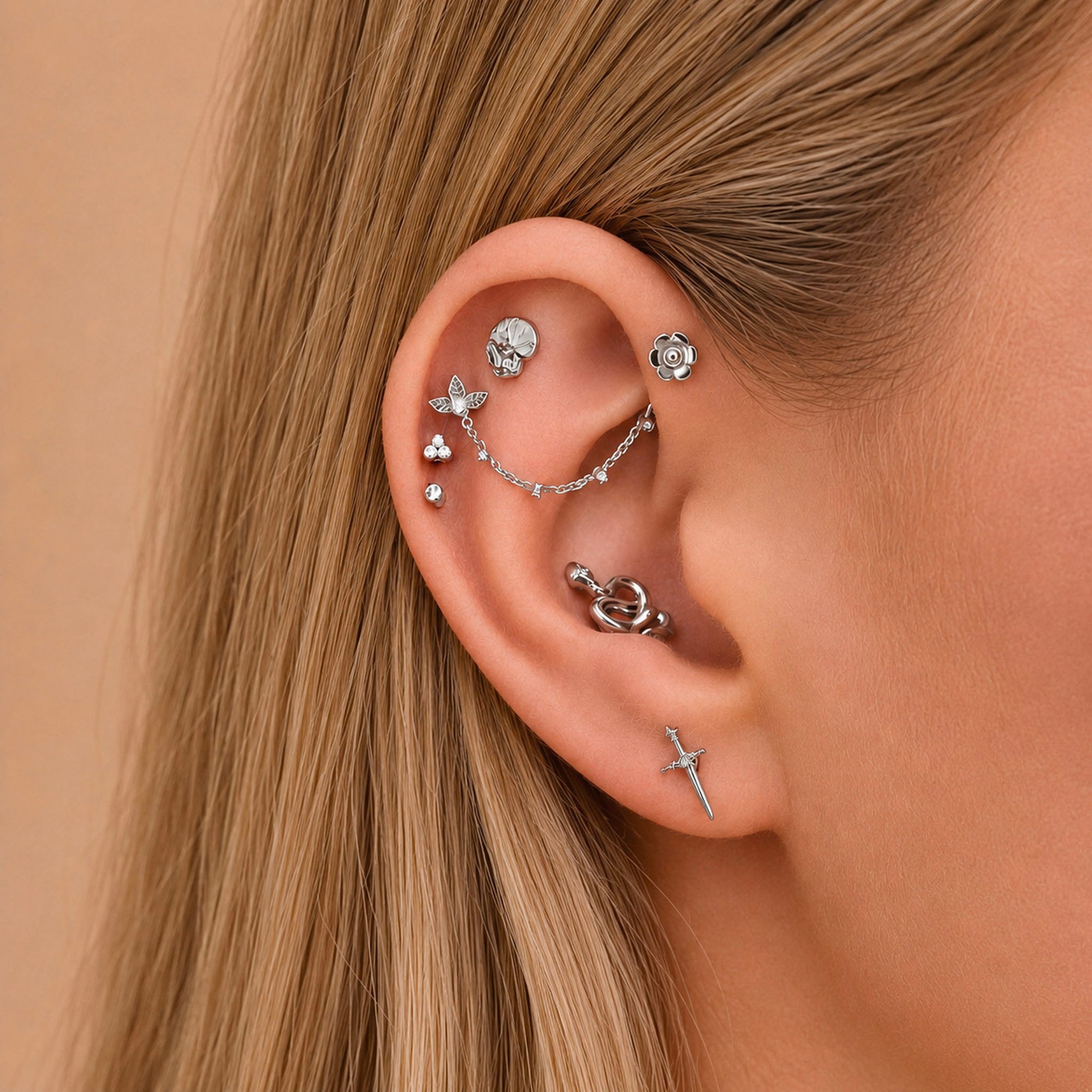 Elegant ear stack with floral, sword, and chain piercings in 18k gold, perfect for luxury body jewelry lovers.