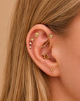 18k gold ear piercings with floral, chain, and sword designs, adorned with tiny diamonds for elegant body jewelry.