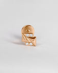 18k gold piercing stud with geometric design and four white gemstones on neutral background