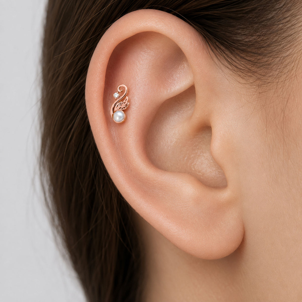 Rose gold helix piercing with a pearl and small diamond in a decorative swirl design