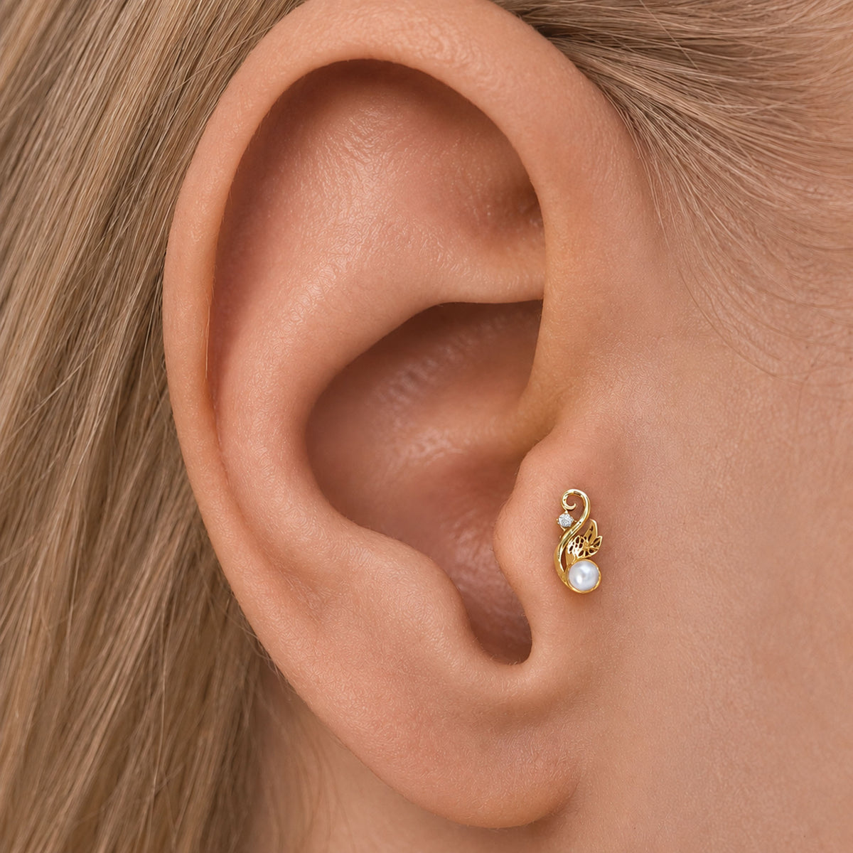 18k gold leaf-shaped tragus piercing with a pearl and small diamond on a human ear