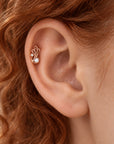 18k gold helix piercing with a pearl and diamond leaf design on a person's ear