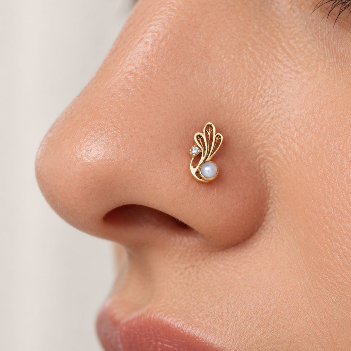 18k gold nose stud with a white pearl and diamond in a decorative swirl design