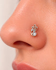 Close-up of a silver nose stud with a pearl and diamond accent on a woman's nostril.