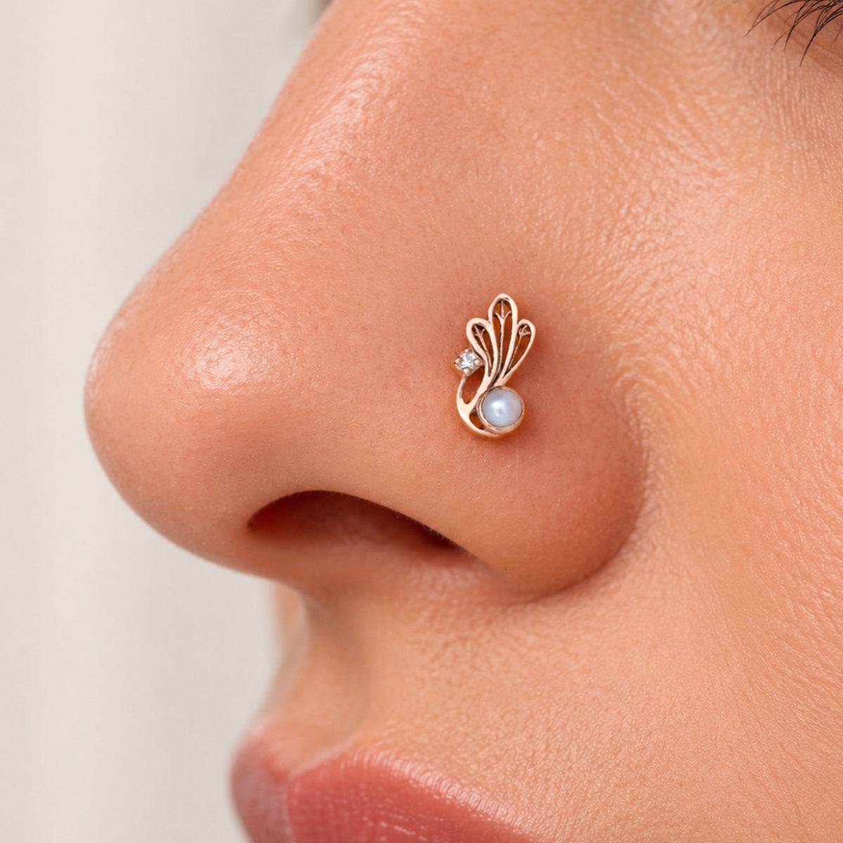 Elegant 18k gold nose stud with a pearl and diamond in a swirling leaf design