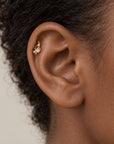 Close-up of a 18k gold helix piercing with a small pearl on a person's ear