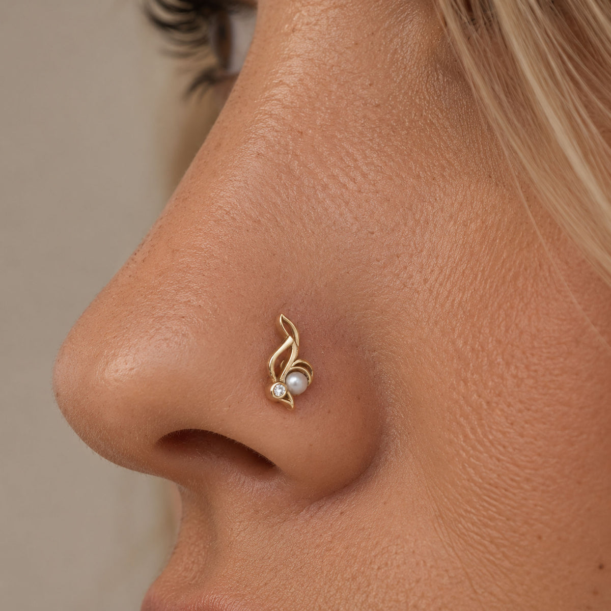18k gold nose stud with a pearl and diamond, shaped like a stylized leaf