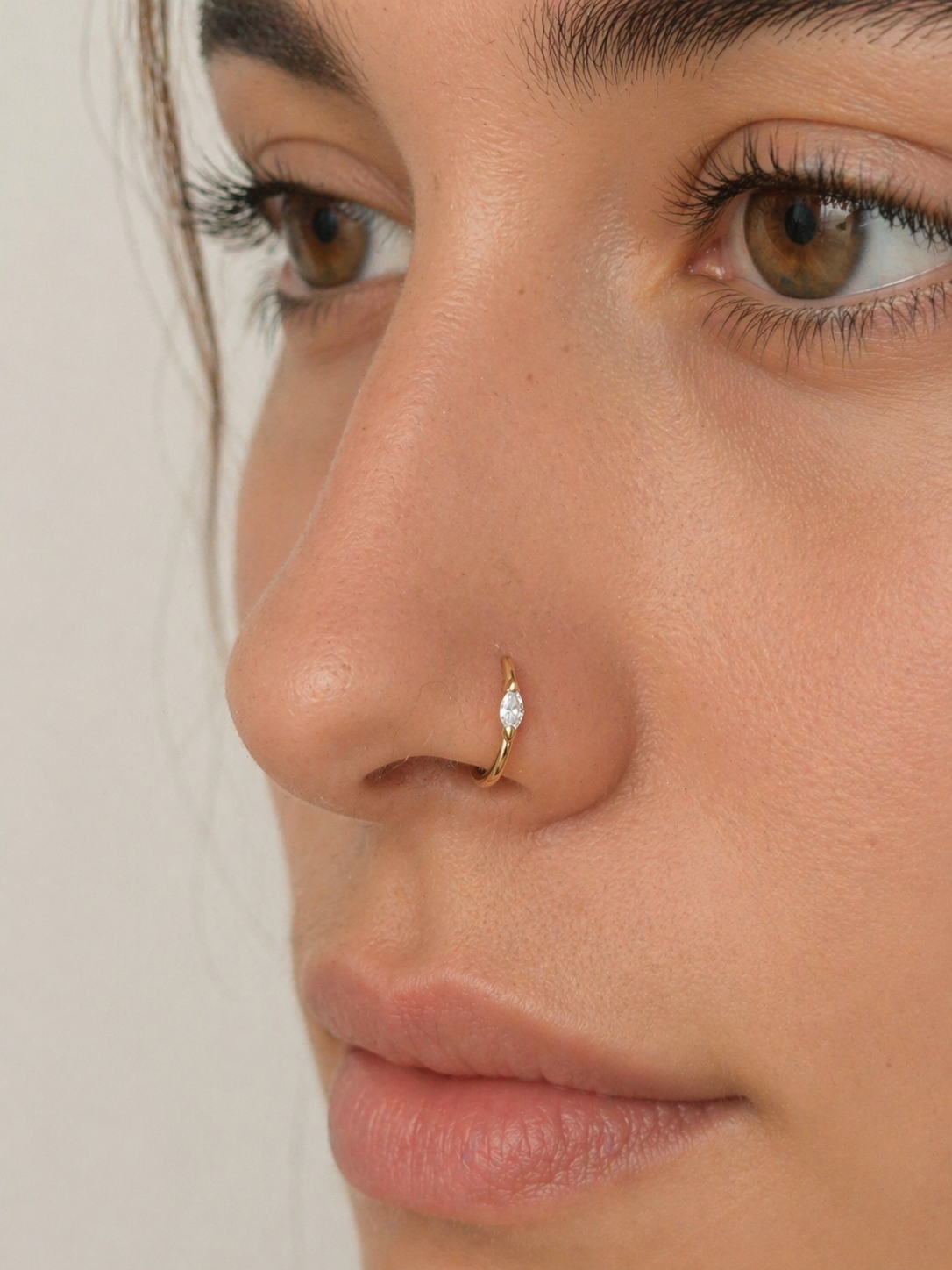 Close-up of a woman wearing an 18k gold nose ring with a marquise diamond