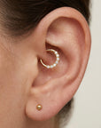 Close-up of ear with a gold cartilage hoop earring adorned with small diamonds