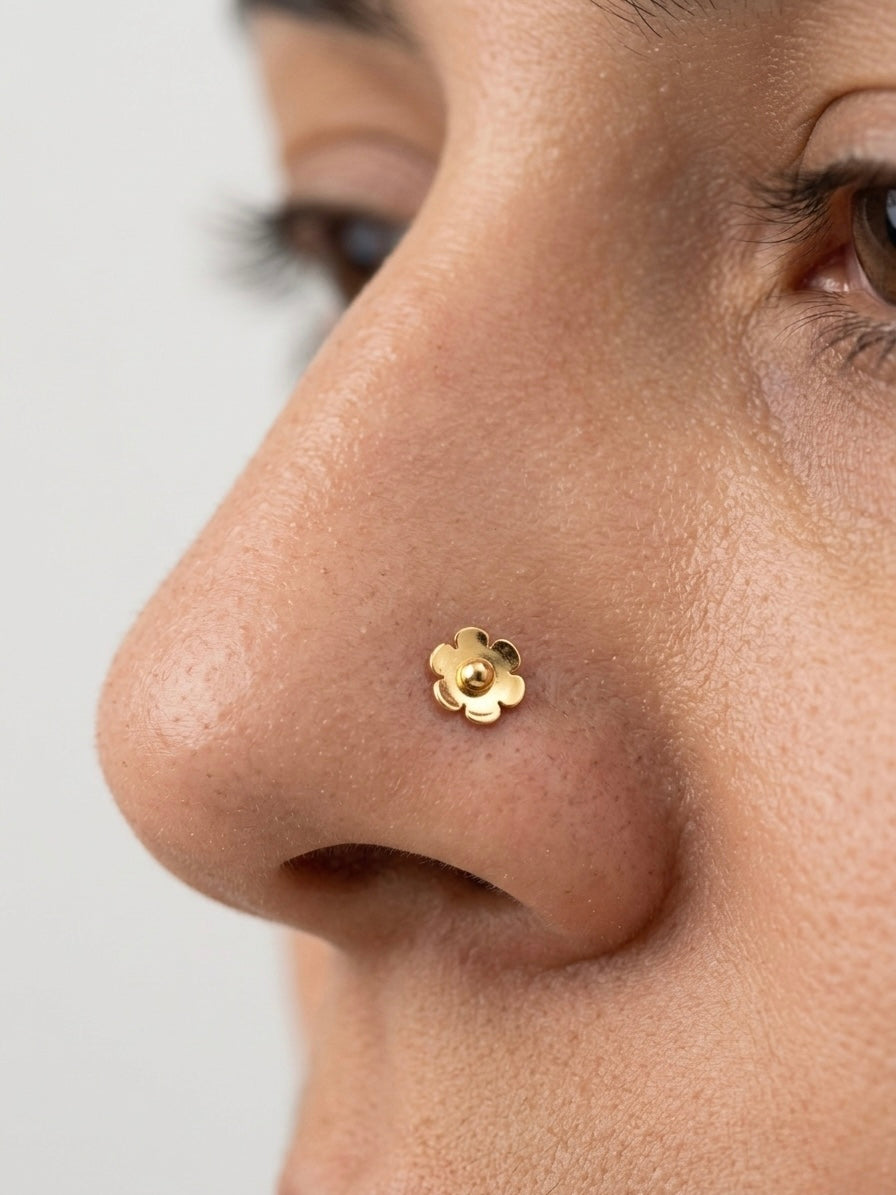 Close-up of a nose with a gold flower-shaped nose piercing stud