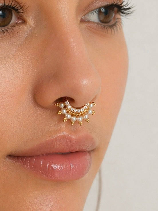 Elegant 18k gold septum piercing with pearls and gemstones on a woman's nose