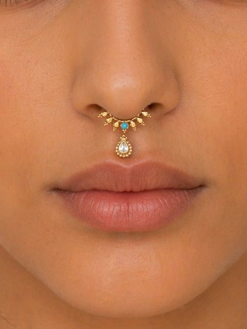 Close-up of nose with 18k gold septum piercing featuring turquoise and teardrop gemstone
