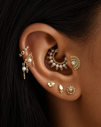 Close-up of ear with multiple 18k gold piercings, pearl accents, and intricate luxury jewelry.