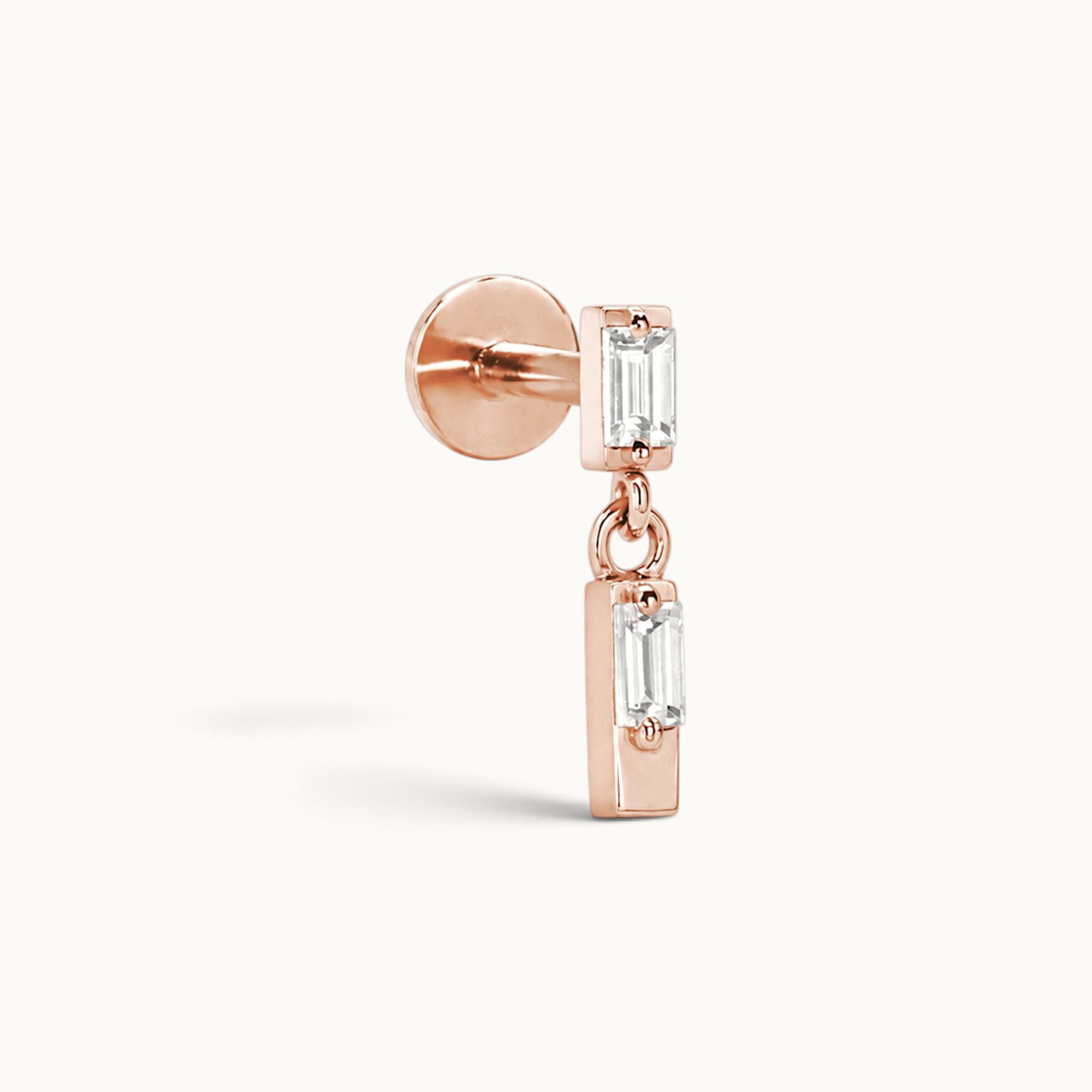 Rose gold ear piercing with dangling baguette-cut gemstones, luxury 18k gold body jewelry