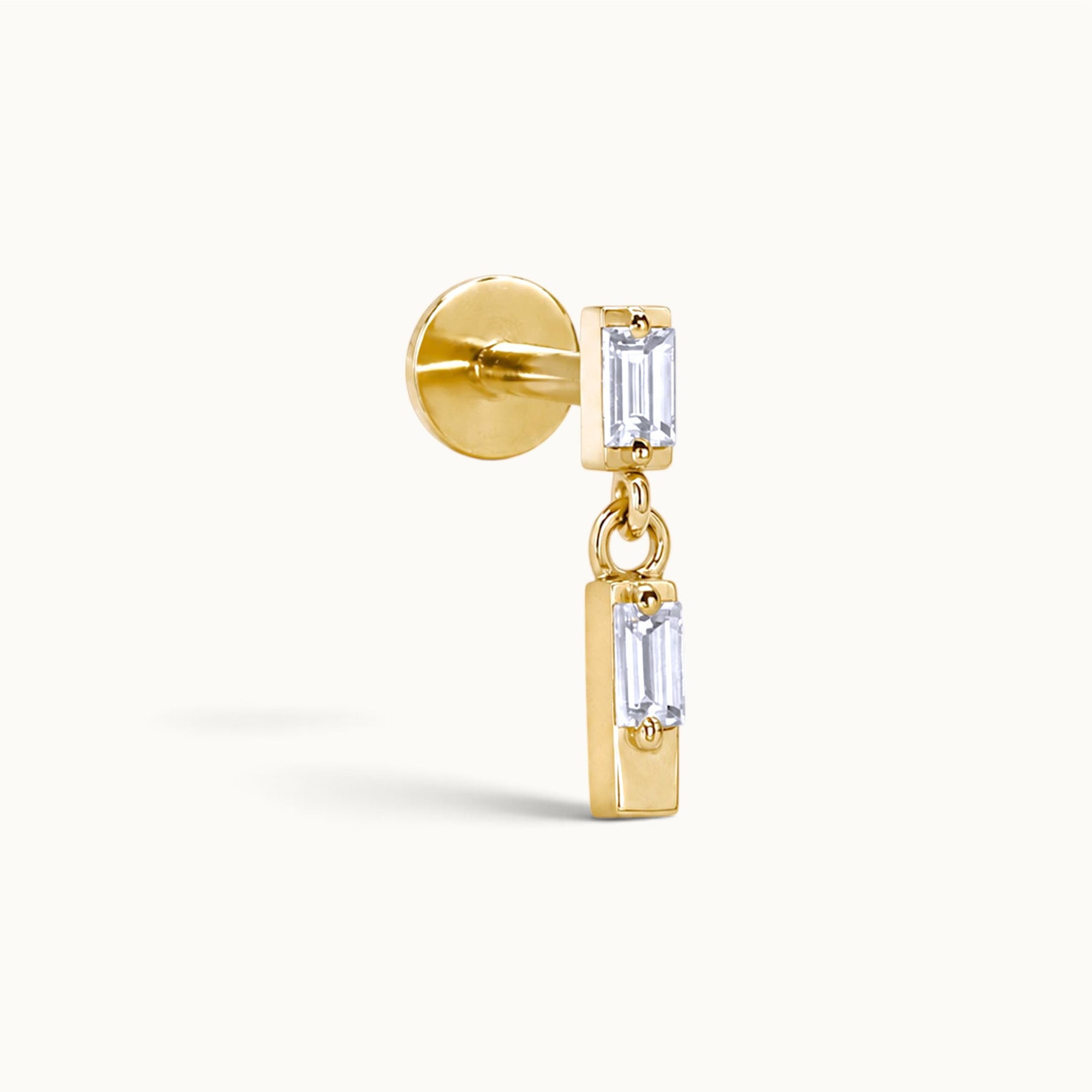 18k gold ear piercing with dangling emerald-cut stones, luxury body jewelry for elegant style