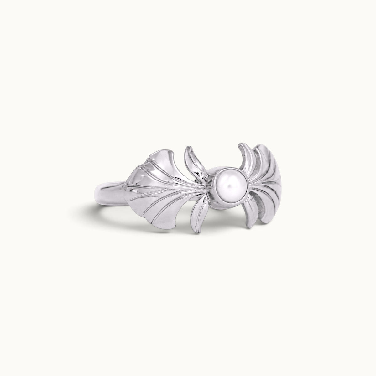 Silver shell-inspired ring featuring a central white pearl on a plain white background