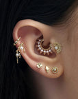 Close-up of an ear with multiple 18k gold and pearl piercings, luxury handmade jewelry.