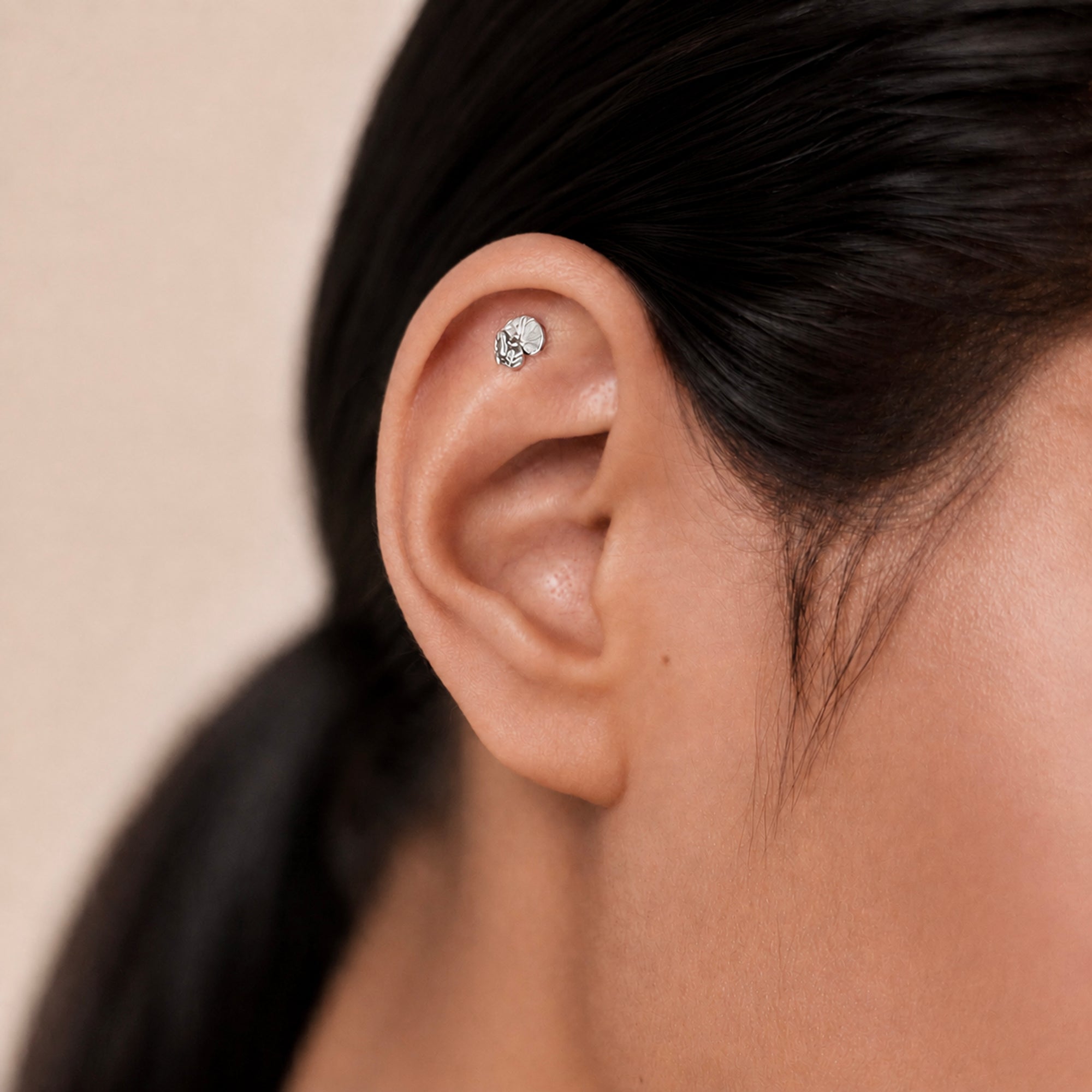 Delicate 18k gold ear piercing with textured disc design, handmade luxury body jewelry for elegant style.