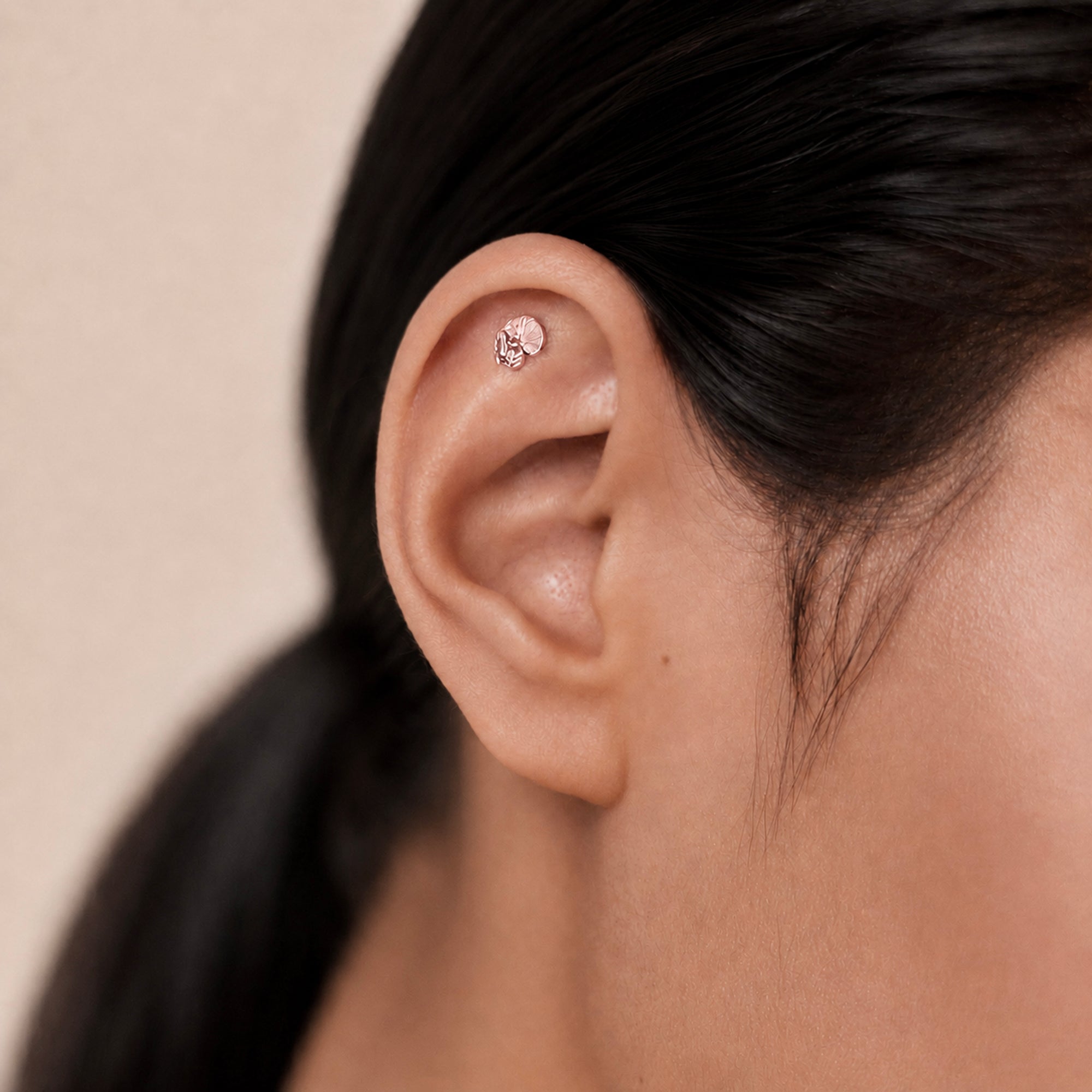 Delicate 18k gold ear piercing with textured stud, showcasing luxury body jewelry for elegant style.