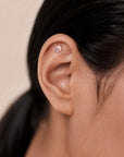 Delicate 18k gold ear piercing with textured stud, showcasing luxury body jewelry for elegant style.